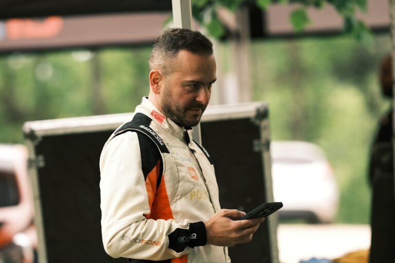 Um Homem De Jaqueta Laranja E Branca Olhando Para Um Celular qEQLj95yNfM