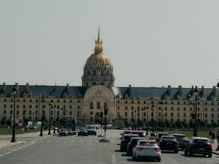 Les Invalides in Paris with city traffic in the foreground under a clear sky.