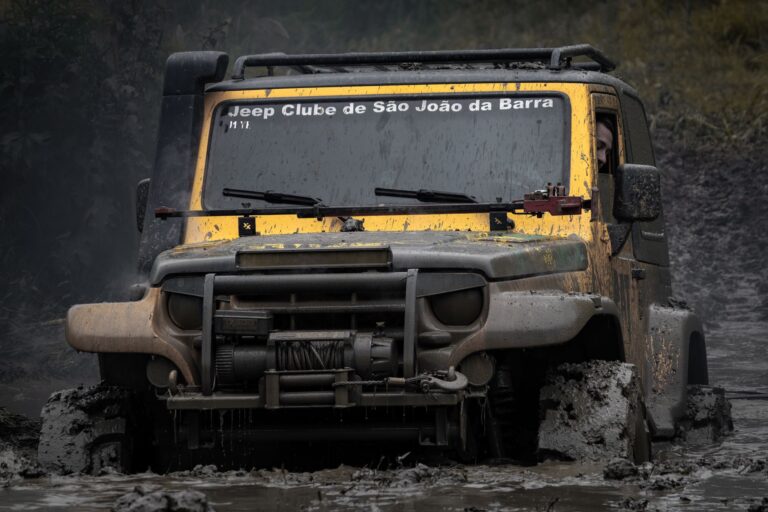 A rugged Jeep navigates through thick mud, showcasing its off-road capabilities.