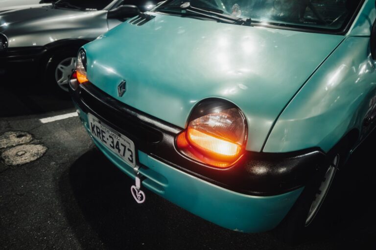 Detailed view of a Renault Twingo's headlights glowing in a parking lot at night, capturing its iconic design.