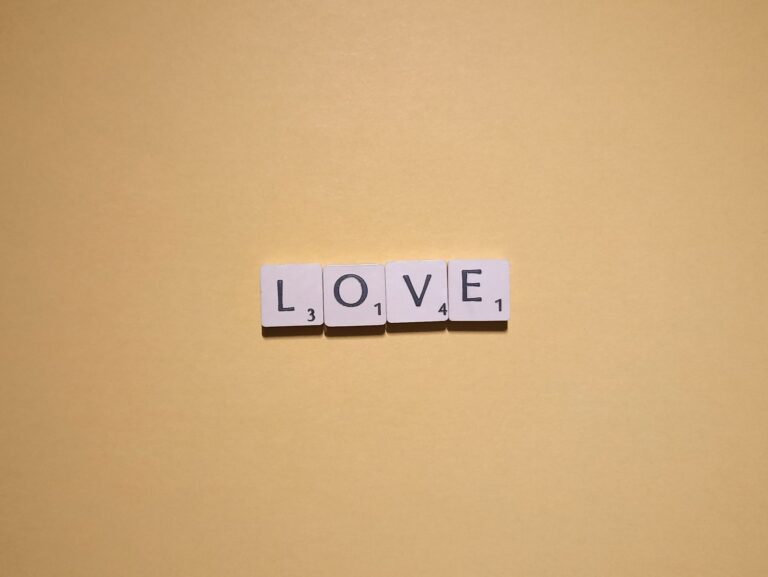 Scrabble tiles spelling 'LOVE' on a warm yellow background, minimalist design.
