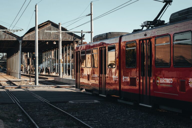 A red electric train at a busy platform in Mendoza, Argentina, during the day.