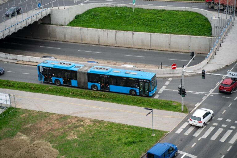 A blue bus navigating city streets from an aerial perspective, showcasing urban transportation.