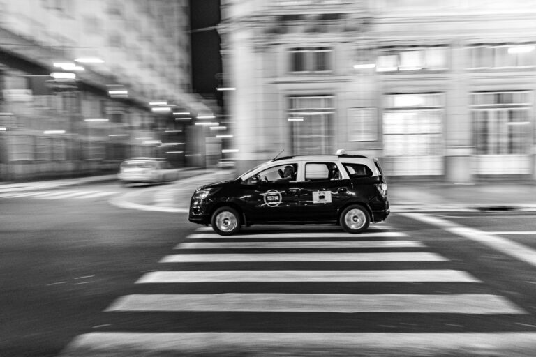 Dynamic black and white photo of a taxi speeding through Buenos Aires at night.