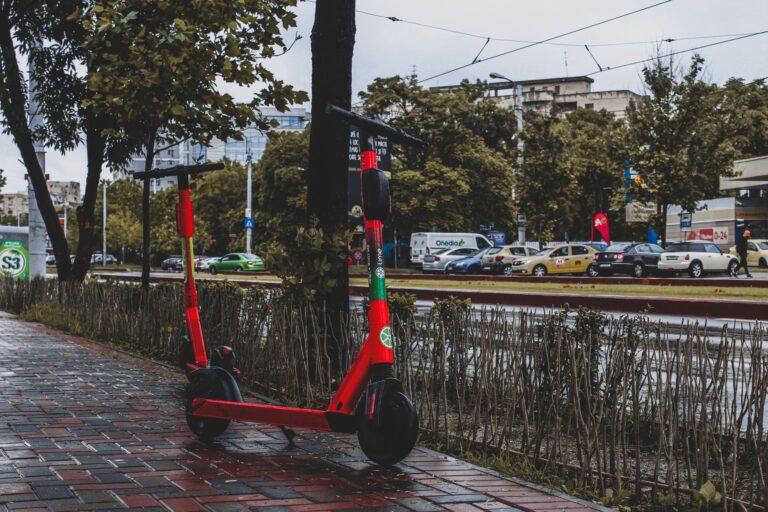 A vibrant red electric scooter parked on a wet sidewalk in Bucharest, showcasing urban mobility.