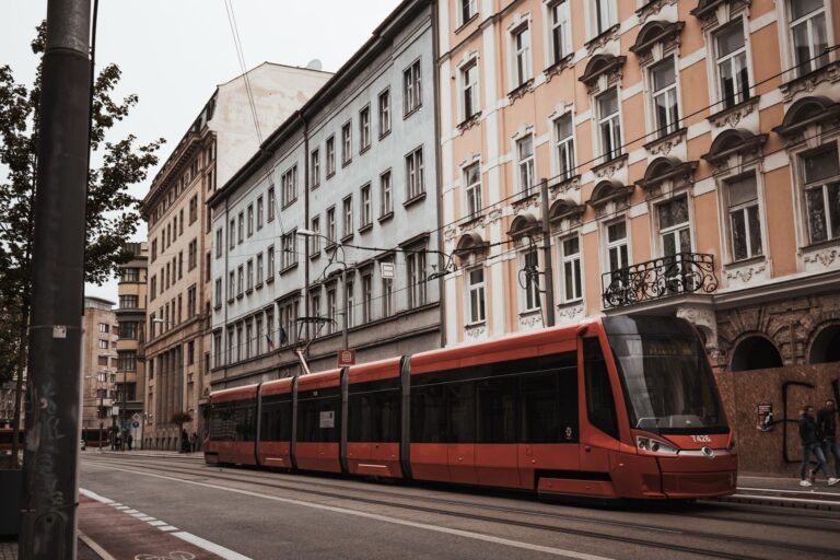 Explore the charm of Bratislava's streets with this classic view of a red tram passing by historic facades.