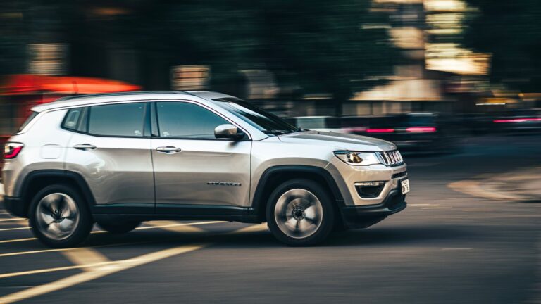 Dynamic side view of a silver SUV speeding downtown, capturing urban motion.