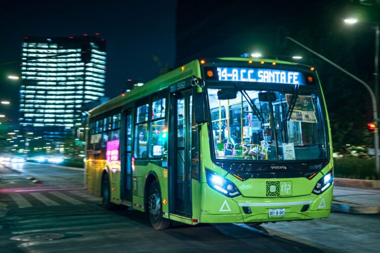 Brightly lit public bus driving in Mexico City at night, showcasing vibrant urban transport.