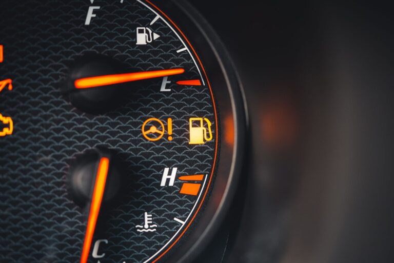 Detailed view of a car dashboard showing fuel and temperature indicators with glowing pictographs.