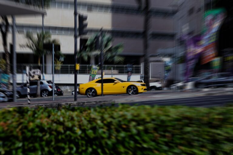 A dynamic shot of a yellow sports car speeding through a bustling city environment in Belo Horizonte.