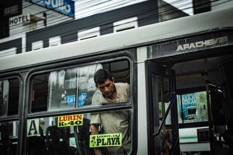 A man onboard a bus in Lima, highlighting the vibrant street culture. Captured in an urban setting.