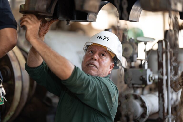 Engineer examines heavy machinery in an industrial site, showcasing technical expertise.