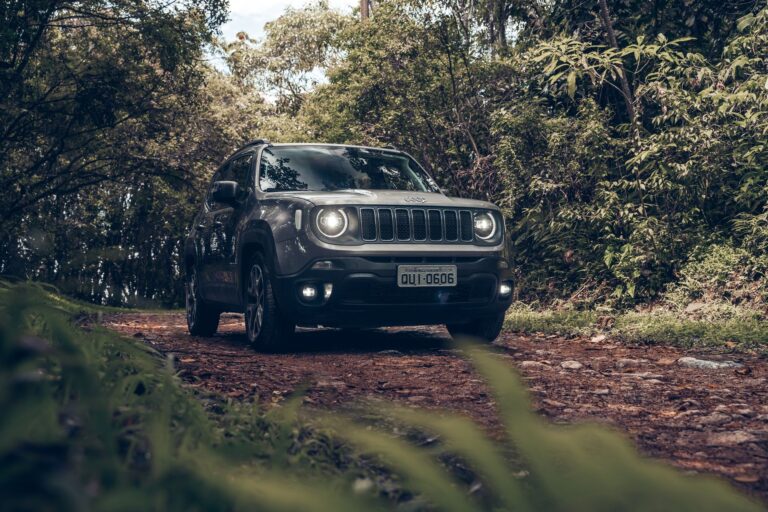 A rugged SUV navigates a dirt road surrounded by lush green trees in São Paulo, Brazil.