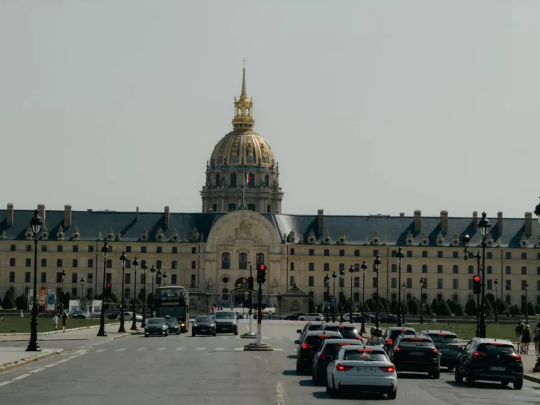 Les Invalides in Paris with city traffic in the foreground under a clear sky.