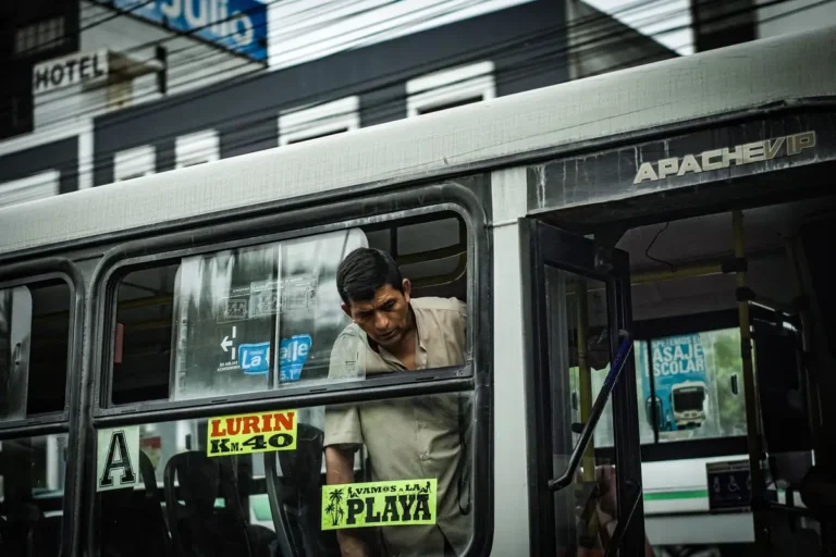 A man onboard a bus in Lima, highlighting the vibrant street culture. Captured in an urban setting.
