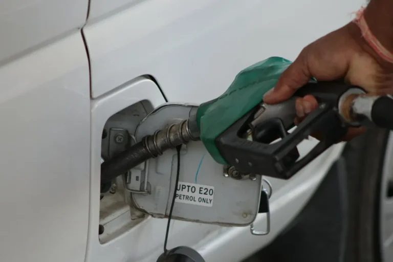 Hand refueling car with E20 petrol at a gas station, close-up view.