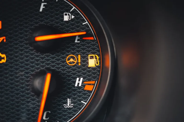 Detailed view of a car dashboard showing fuel and temperature indicators with glowing pictographs.