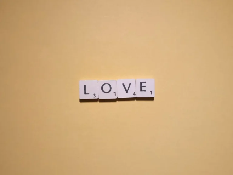Scrabble tiles spelling 'LOVE' on a warm yellow background, minimalist design.