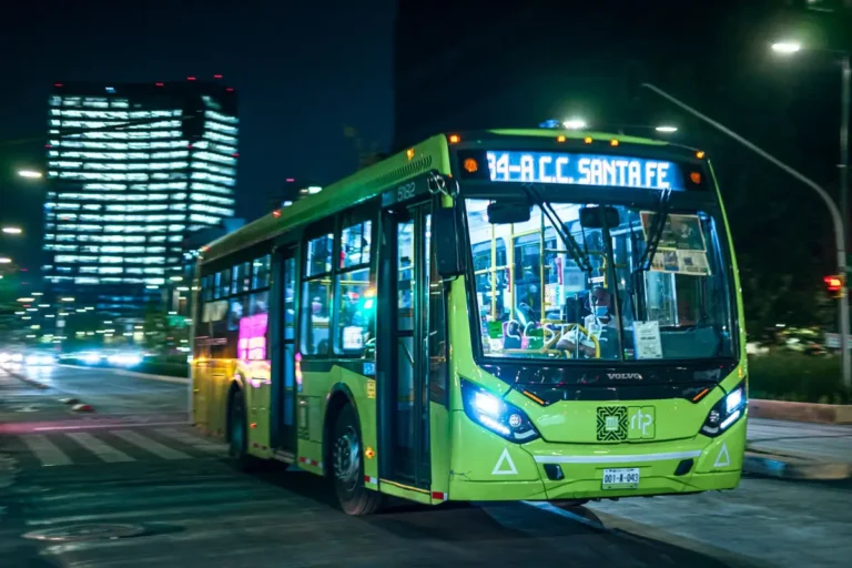 Brightly lit public bus driving in Mexico City at night, showcasing vibrant urban transport.