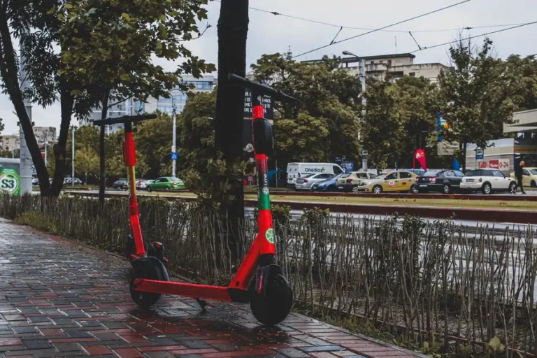 A vibrant red electric scooter parked on a wet sidewalk in Bucharest, showcasing urban mobility.